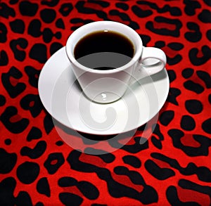 A cup of coffee  on a red leopard board