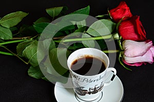 Cup of coffee and red roses on black background, top view