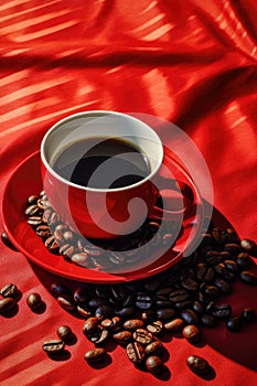 A cup of coffee on a red tray with several coffee beans spilling out