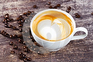 Cup of coffee and roasted bean on old wooden table