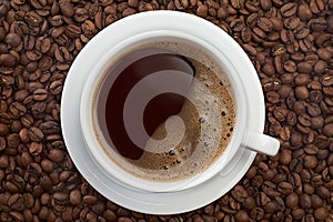 Cup of coffee on roasted beans background