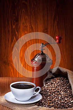 Cup of coffee with roasted beans and coffee grinder