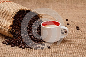 Cup of coffee and roasted coffee beans in a canvas sack