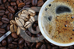 Cup of coffee, roasted coffee beans and golden coffee beans in a spoon. The concept of luxury and originality.