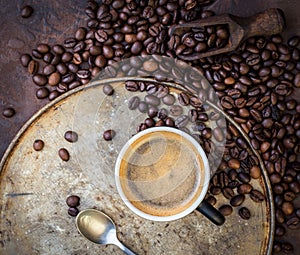 Cup of coffee on rustic steel background with coffee beans aroun