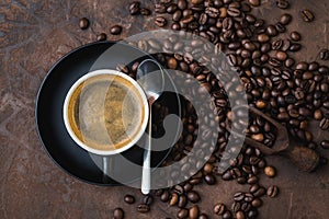 Cup of coffee on rustic steel background with coffee beans aroun