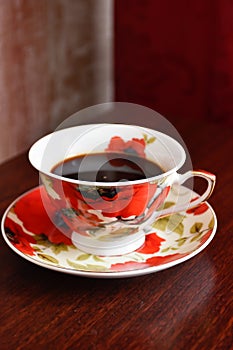 A cup of coffee on a saucer with poppies.