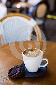 Cup of coffee served with chocolate cookie.