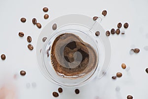 a cup with coffee in the shape of a heart and scattered grains on a white background, coffee and romance