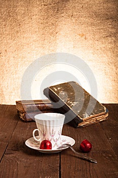 Cup of coffee, shokolad and stack of old books on the old wooden