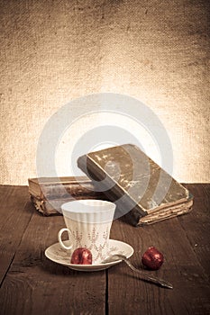 Cup of coffee, shokolad and stack of old books on the old wooden
