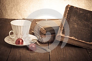 Cup of coffee, shokolad and stack of old books on the old wooden