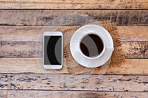 Cup of coffee with smart phone on a wooden table background.