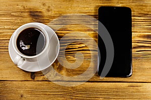 Cup of coffee and smartphone on wooden table