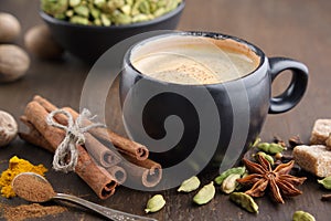 Cup of coffee with spices. Cinnamon sticks, cardamom, allspices, curcuma and anise on wooden table