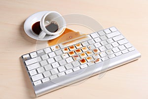 Cup of coffee spilled over computer keyboard on wooden table