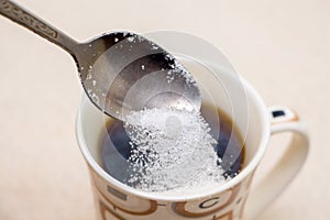 Cup of coffee and spoonful of sugar, sugar is poured into coff