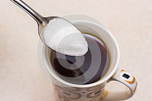 Cup of coffee and spoonful of sugar, sugar is poured into coff