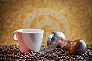 Cup of coffee with stamper and coffee beans on gold background, product photography for coffee shop