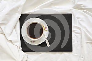 Cup of cappuccino standing on a book and a white sheet photo