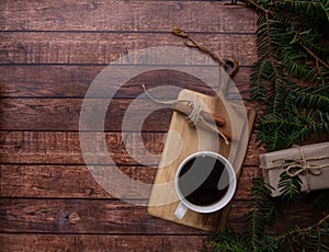 A cup of coffee stands on a cutting board on a wooden table