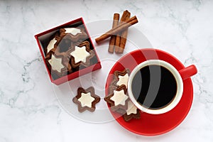 Cup of coffee with star shaped cookies, cinnamon sticks and christmas decorations on white marble table. Christmas background.