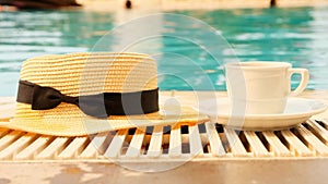 cup of coffee and a straw hat on the background of a swimming pool on a summer sunny day. Good morning concept and