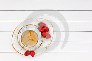 Cup of coffee and strawberries on white wooden table. Top view