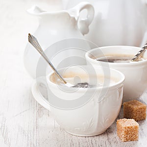 Cup of coffee with sugar cubs and milk jug