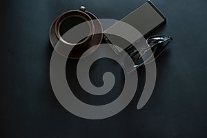 cup of coffee, sun glasses, smartphone on a black background