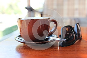 A cup of coffee with sunglasses on the table