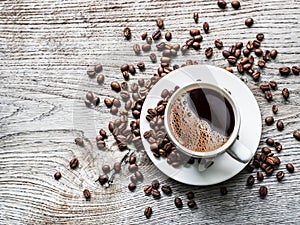 Cup of coffee surrounded by coffee beans. Top view.