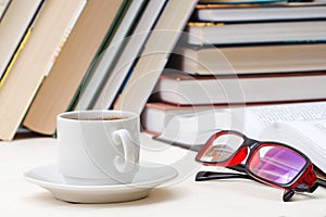 Cup of coffee on the table against the background of the books