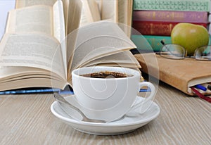 A cup of coffee on the table against the background of an open b