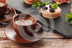 Cup of coffee on the table and a fruit basket on a serving board, fruit muffin with berries