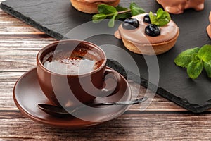 Cup of coffee on the table and a fruit basket on a serving board, fruit muffin with berries