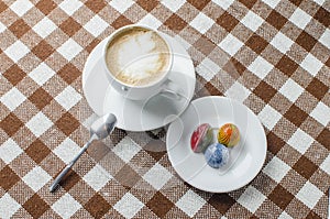 A cup of coffee on a table with sweets