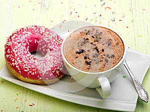 Cup of coffee and tasty donuts with pink icing
