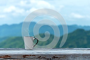 Cup coffee and tea with steam on wood table outdoor over mountains landscape with sunlight. Beauty nature background