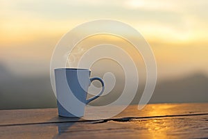 Cup coffee and tea with steam on wood table outdoor over mountains landscape with sunlight. Beauty nature background.