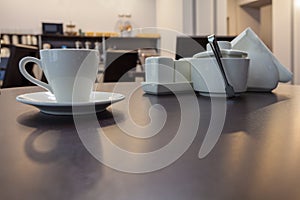 A cup of coffee tea on the wooden round table in modern cafe with furniture of kitchen on the background.