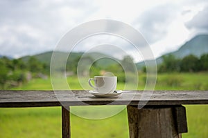Cup of coffee or tea on a wooden table over mountains landscape and rice field with sunlight. Beauty nature background