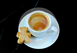 Cup of Coffee with Teddy Bear Shaped Cookie Isolated on Black Marble Table