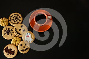 A Cup of coffee, terribly tasty cookies with terrible emoticons, cobwebs, spiders, bats, pumpkins on a black background.