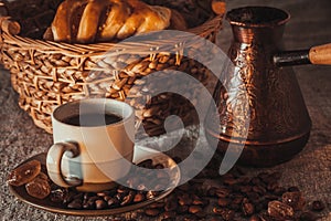 Cup of coffee on textile with beans, dark candy sugar, pots, basket and cake