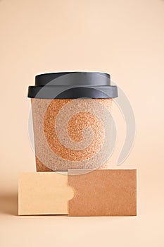 A cup for coffee to go. Business card mockup, eco kraft paper on a beige background