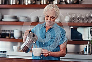 A cup of coffee to start the day. an attractive senior woman pouring herself a cup of coffee while standing in the