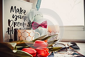 Cup of coffee, toy and tulips flowers on white wooden background