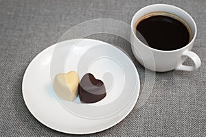 Cup of coffee and two heart-shaped chocolates