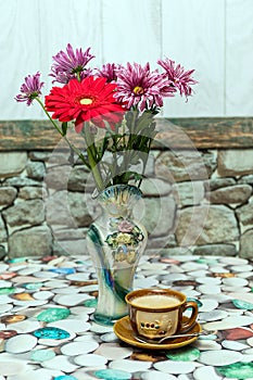 Cup of coffee and vase with flowers on the table.